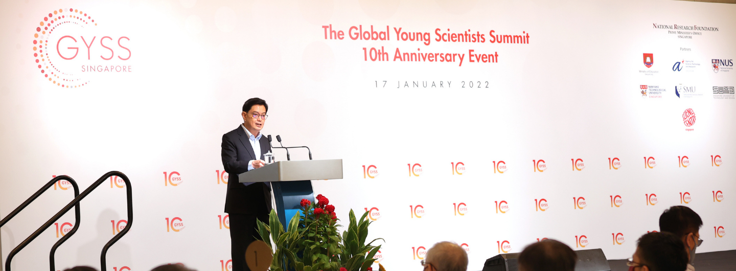 Man at podium speaking at GYSS Global Young Scientists Summit 10th Anniversary event.